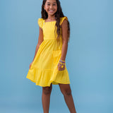 Vestido amarelo infantil com alças largas e saia rodada, detalhe de botões nas alças