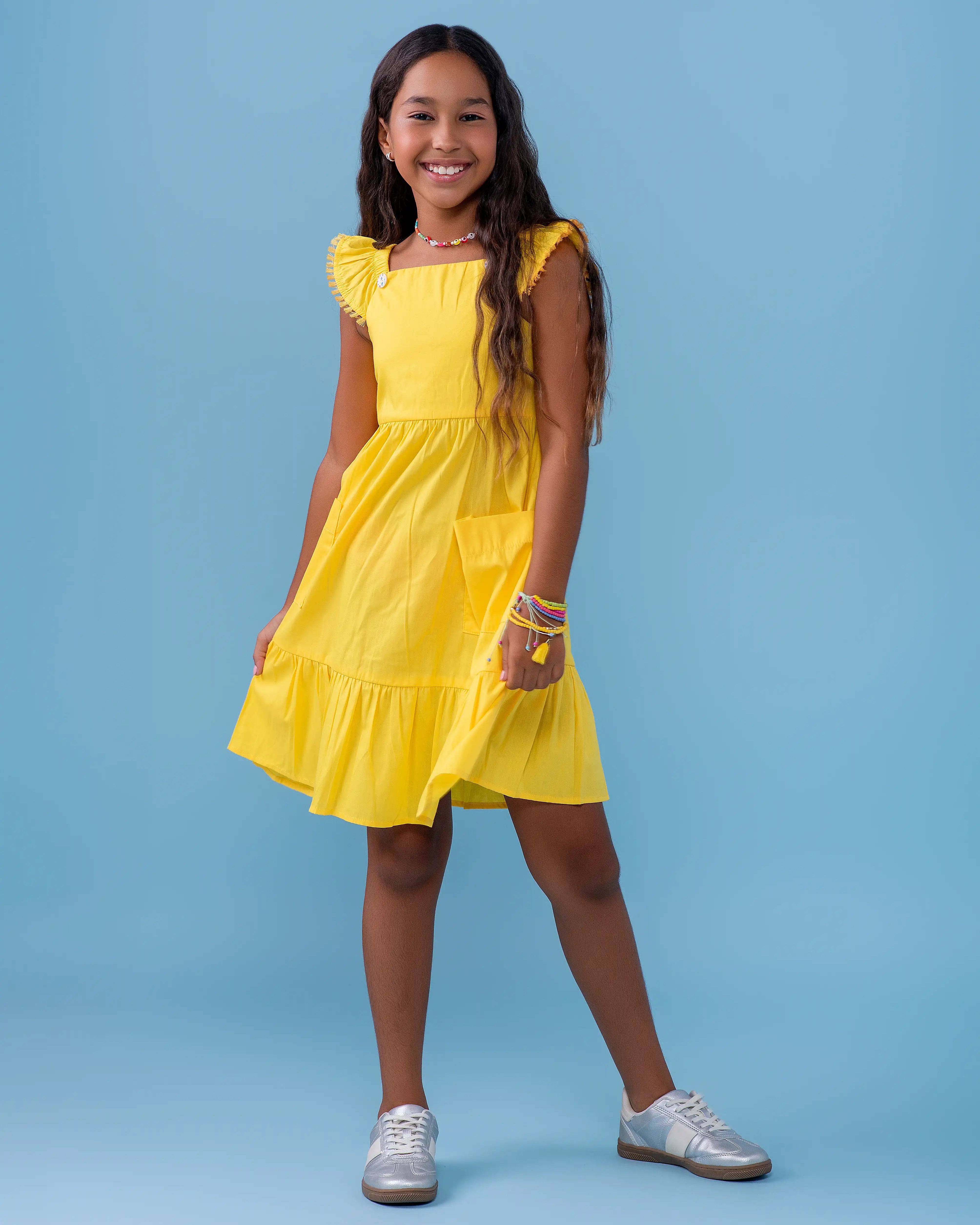 Vestido amarelo infantil com alças largas e saia rodada, detalhe de botões nas alças