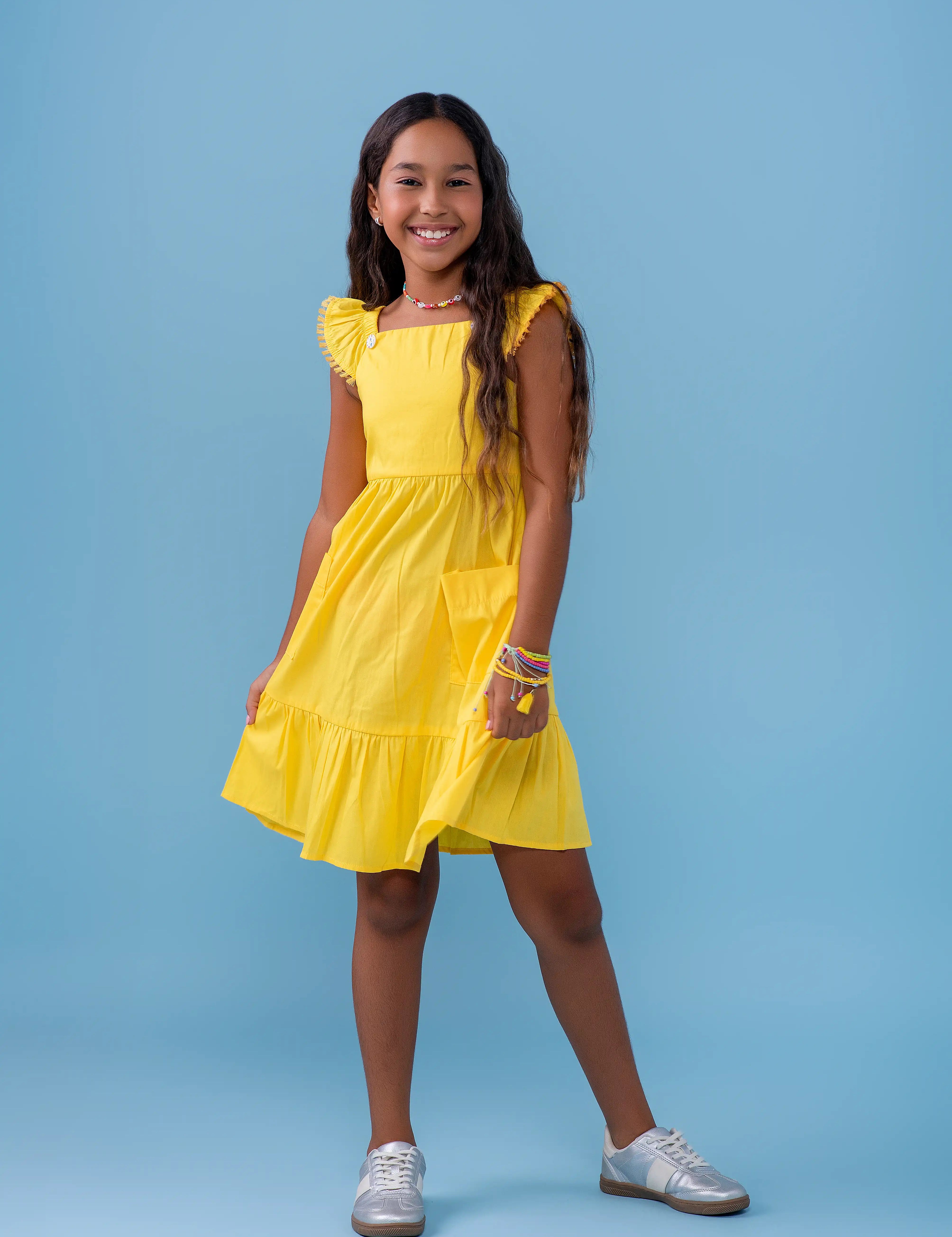 Vestido amarelo infantil com alças largas e saia rodada, detalhe de botões nas alças