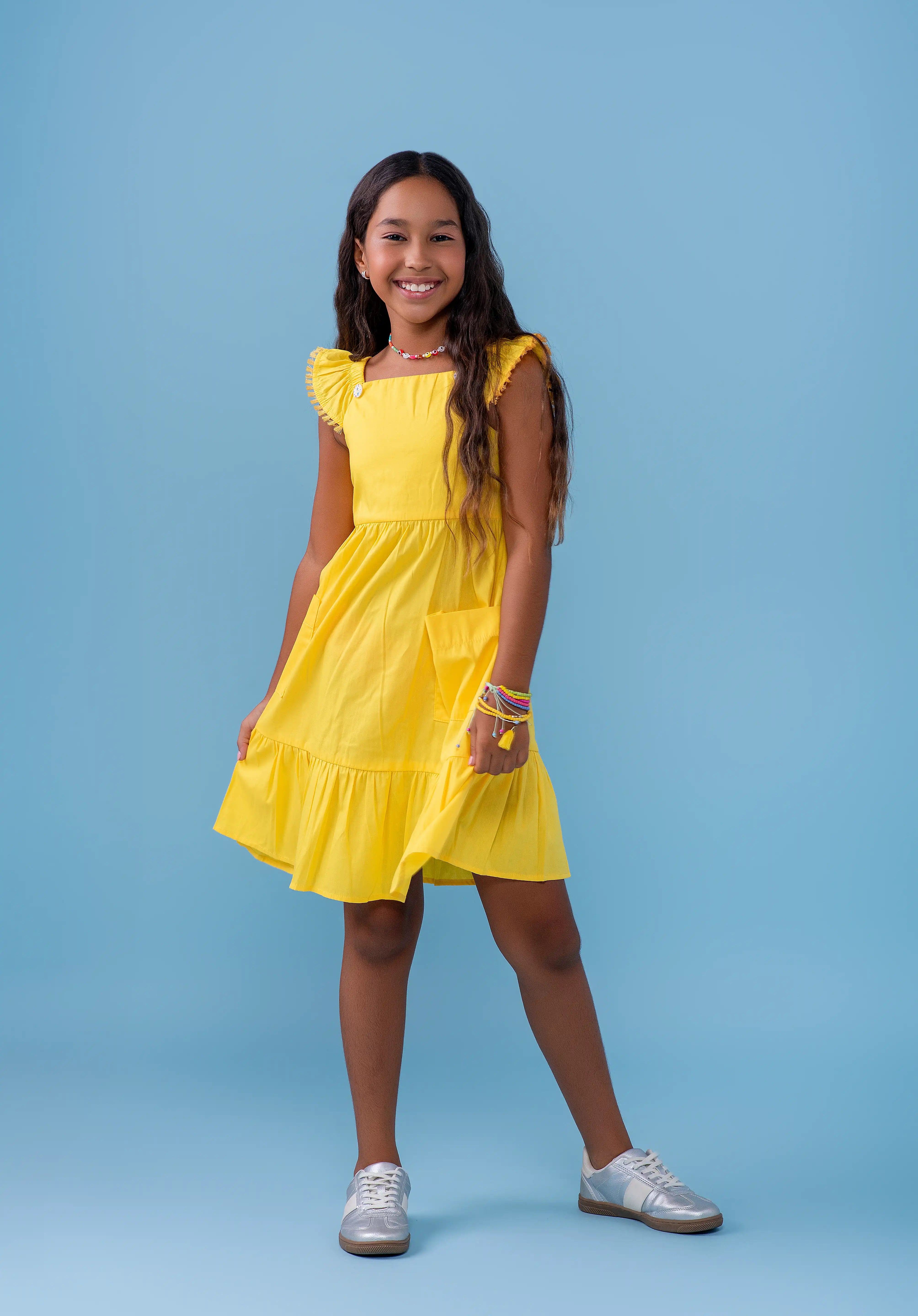 Vestido amarelo infantil com alças largas e saia rodada, detalhe de botões nas alças