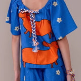 Conjunto infantil feminino com blusa azul de mangas bufantes e saia-short, estampa de cães salsichas e flores