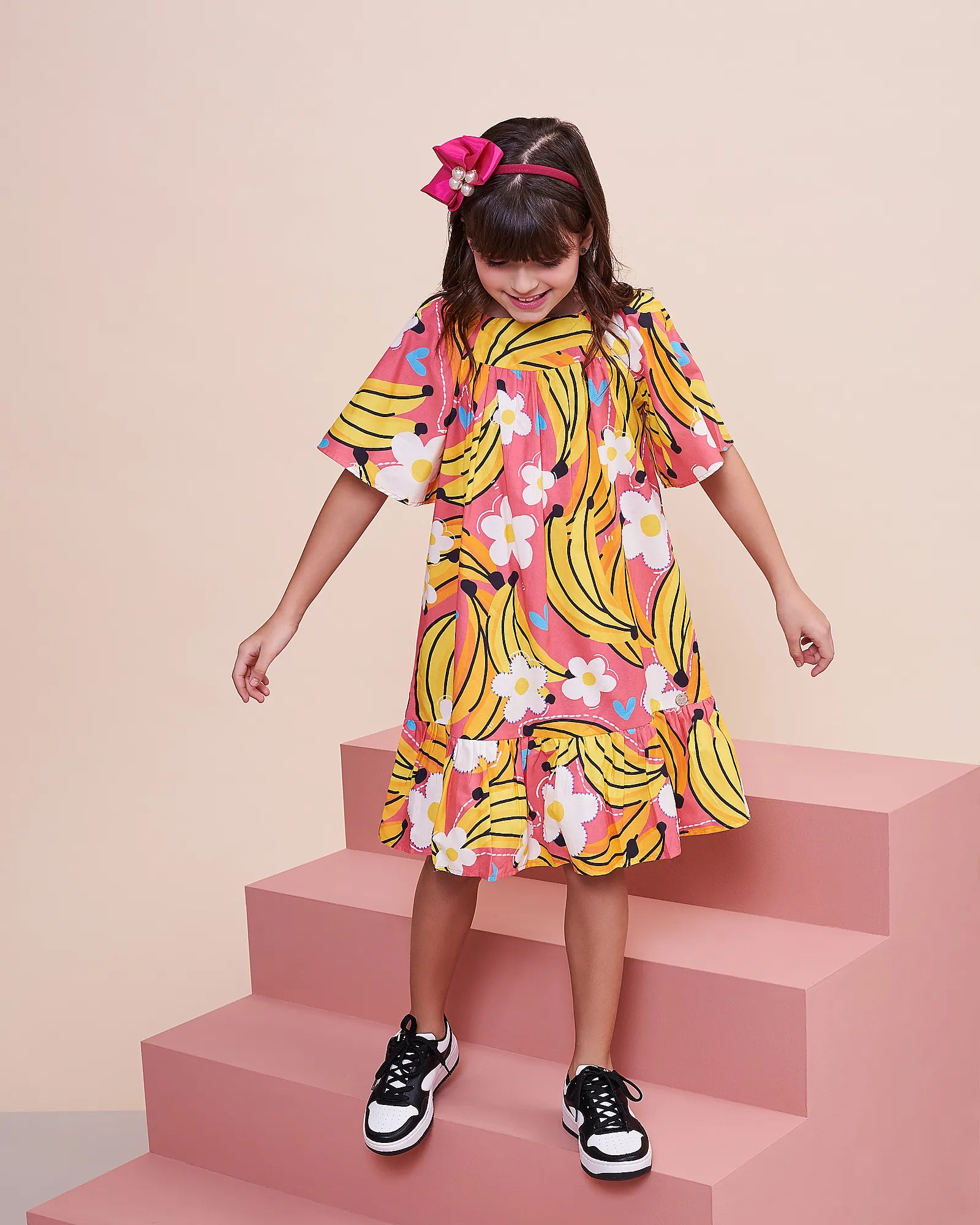 Vestido infantil com estampa de bananas e flores, mangas amplas e saia em camadas