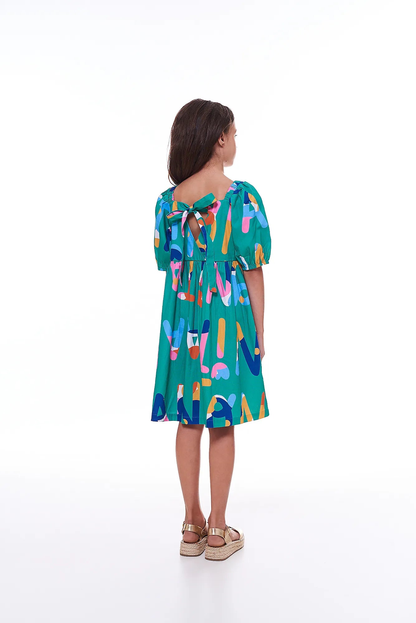 Vestido infantil com padrão de letras coloridas e mangas bufantes, detalhe de cintura marcada