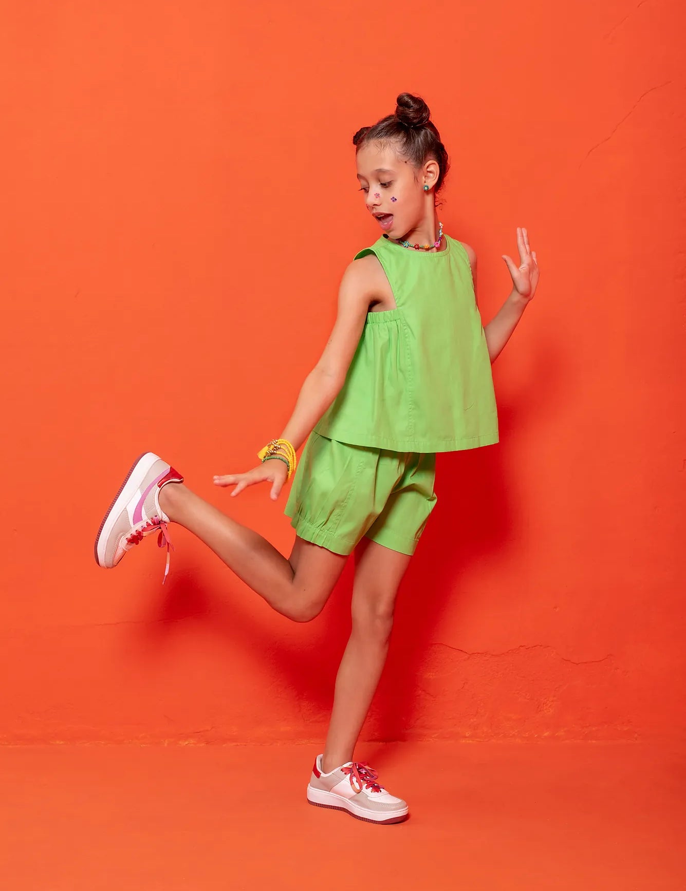 Conjunto infantil feminino com blusa verde de alças largas e short leve, ideal para brincadeiras.