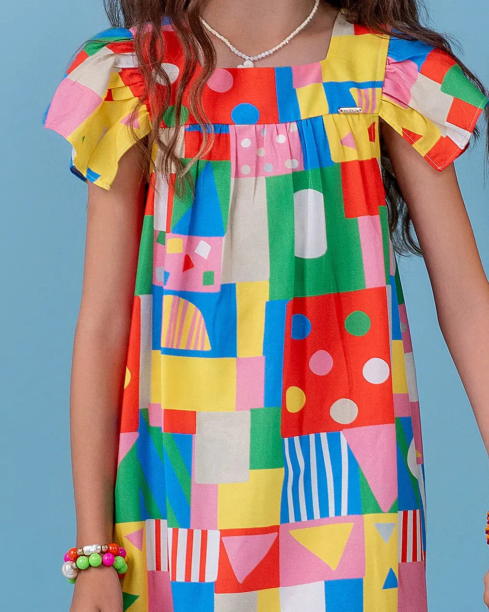 Vestido infantil com estampa de blocos coloridos e alças em babados
