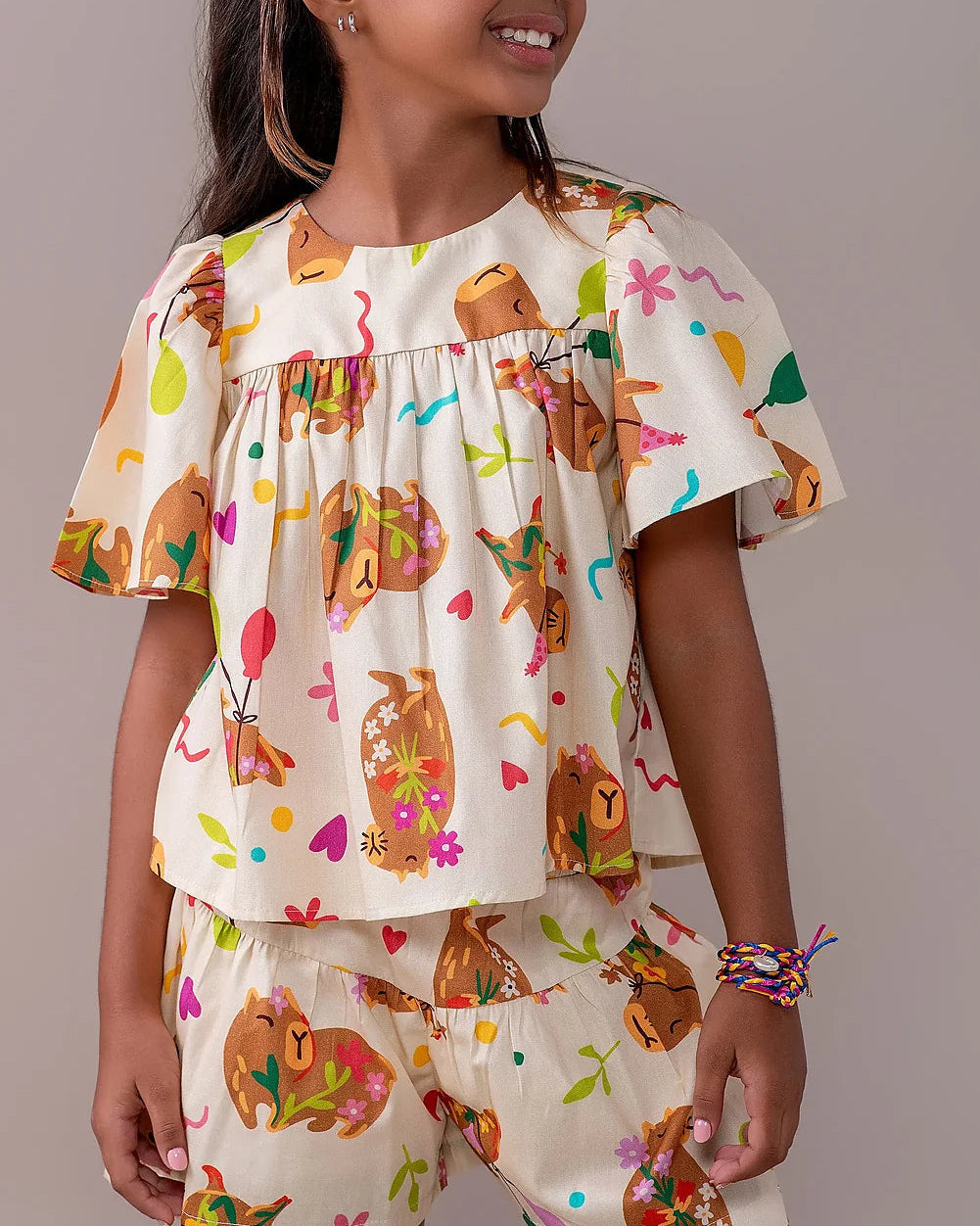 Conjunto infantil feminino com blusa de mangas amplas e saia, estampa de capivaras e balões coloridos