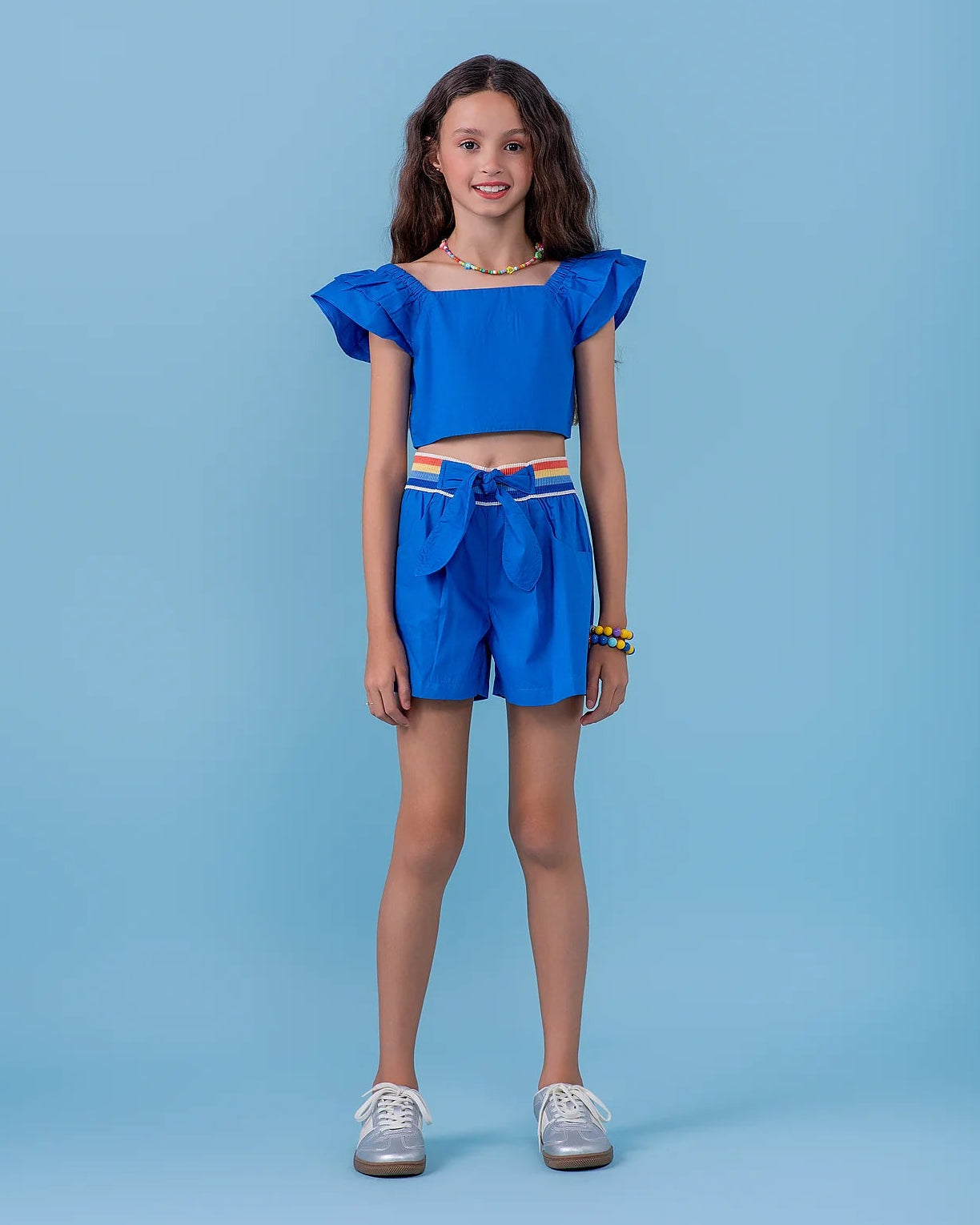 Conjunto feminino infantil azul com blusa de alças largas e saia-short com faixa colorida