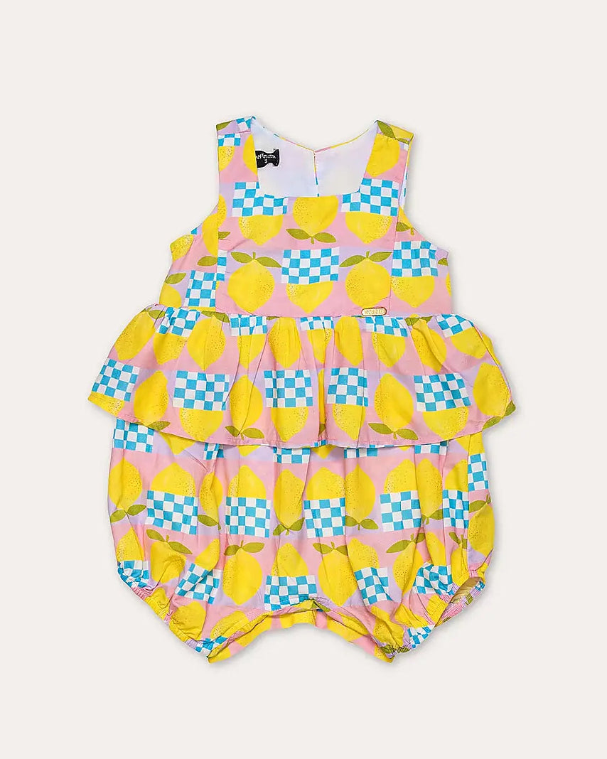 Macacão feminino infantil com estampa de limões e quadrados coloridos, alças largas e saia em camadas.