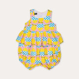 Macacão feminino infantil com estampa de limões e quadrados coloridos, alças largas e saia em camadas.