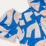 Vestido infantil com estampa geométrica em azul e creme, mangas amplas e gola arredondada