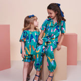 Macacao infantil feminino com padrão de letras coloridas em fundo azul e punhos ajustáveis