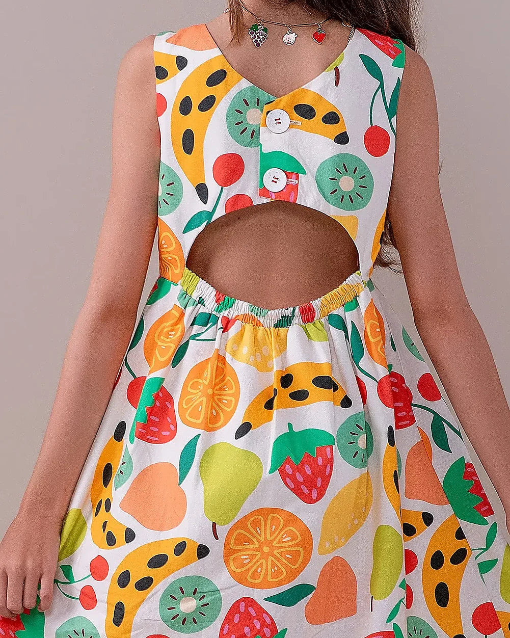 Vestido feminino infantil com estampa de frutas coloridas em fundo claro, alças largas e saia solta