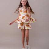 Macacão infantil com estampa de capivaras e flores, alças largas e camadas na parte inferior