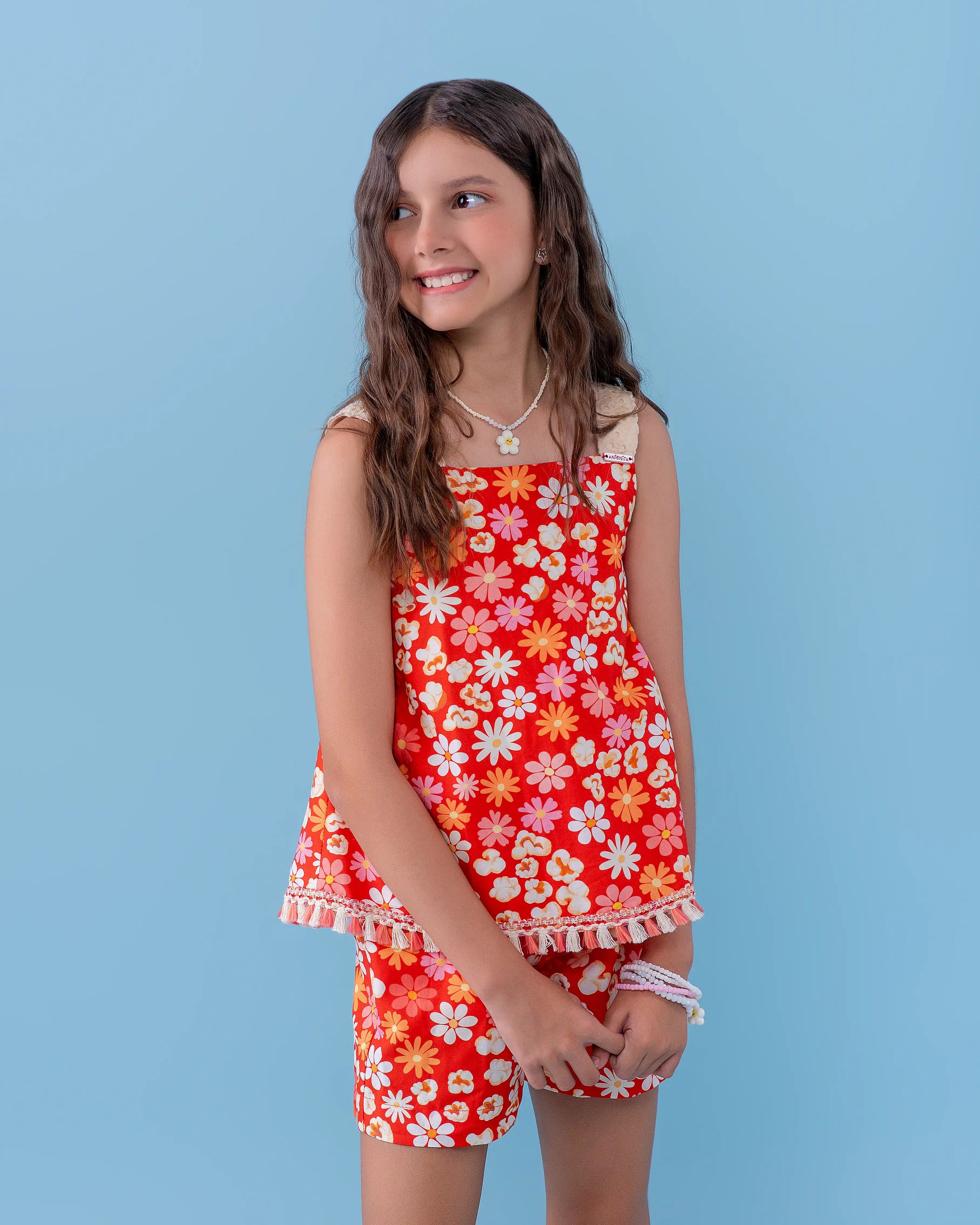 Macacão floral vermelho com alças largas e detalhes em flores brancas, feminino infantil.