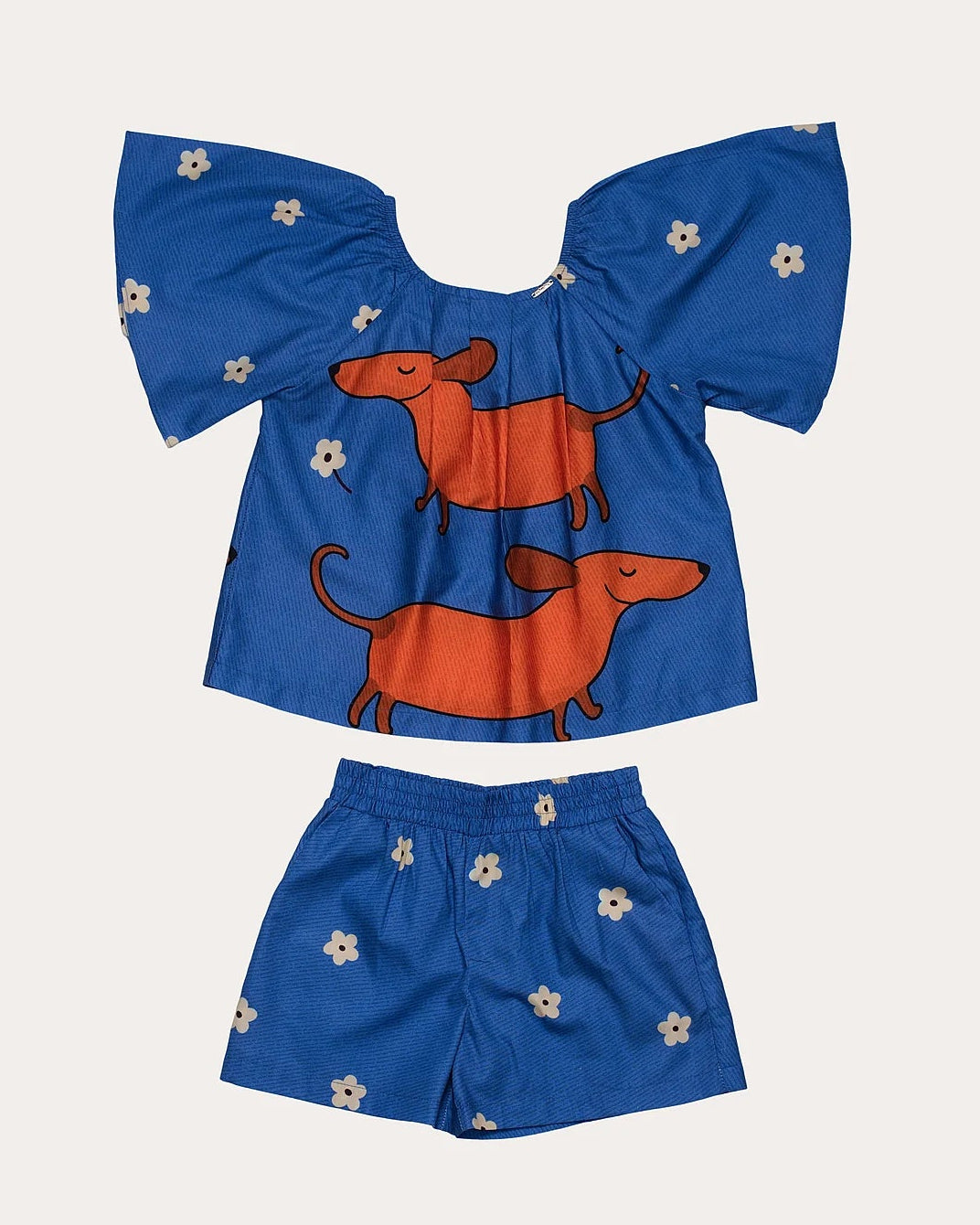 Conjunto infantil feminino com blusa azul de mangas bufantes e saia-short, estampa de cães salsichas e flores