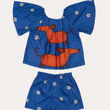 Conjunto infantil feminino com blusa azul de mangas bufantes e saia-short, estampa de cães salsichas e flores