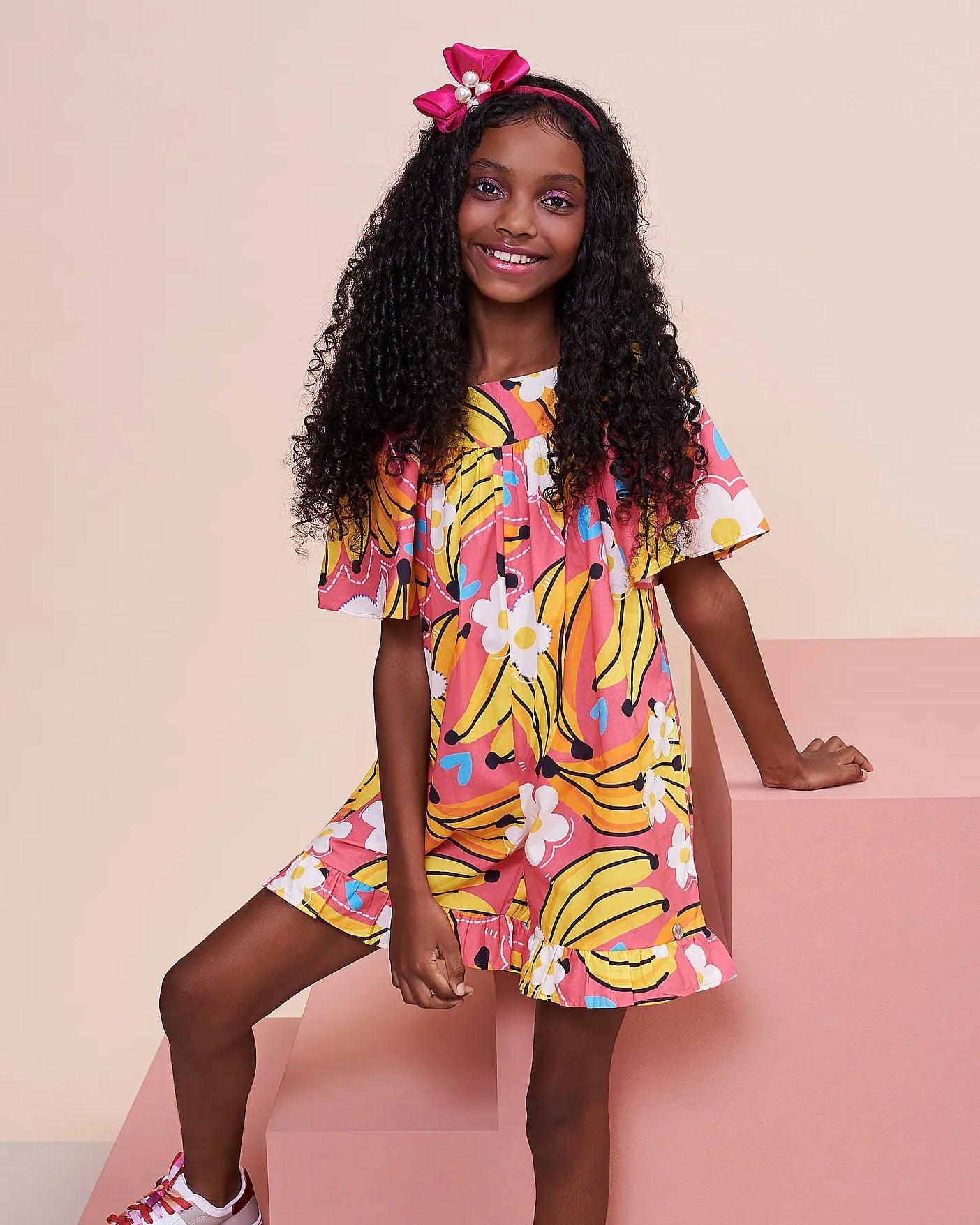 Macaco feminino infantil com estampa de bananas e flores em fundo rosa, detalhe de mangas amplas