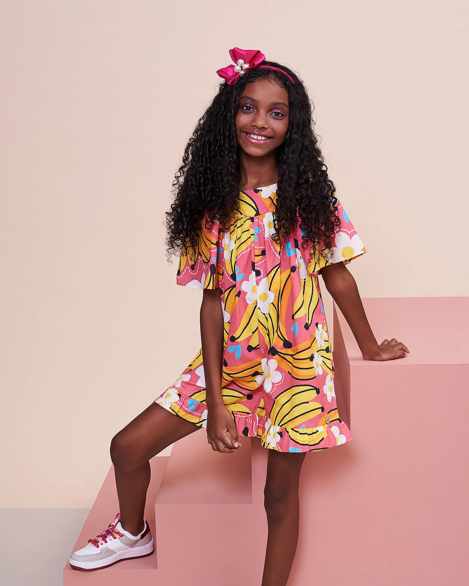 Macaco feminino infantil com estampa de bananas e flores em fundo rosa, detalhe de mangas amplas