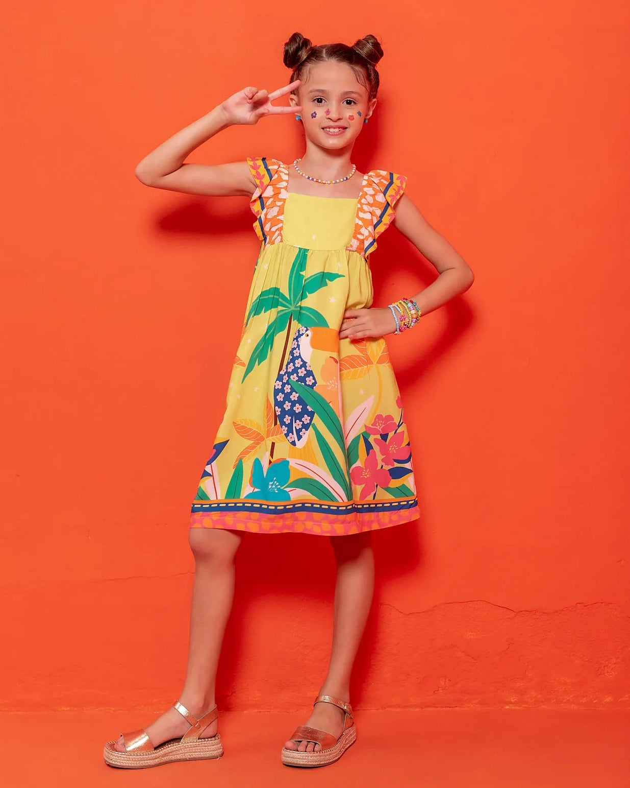 Vestido infantil com estampa tropical de flores e folhas coloridas, alças largas listradas
