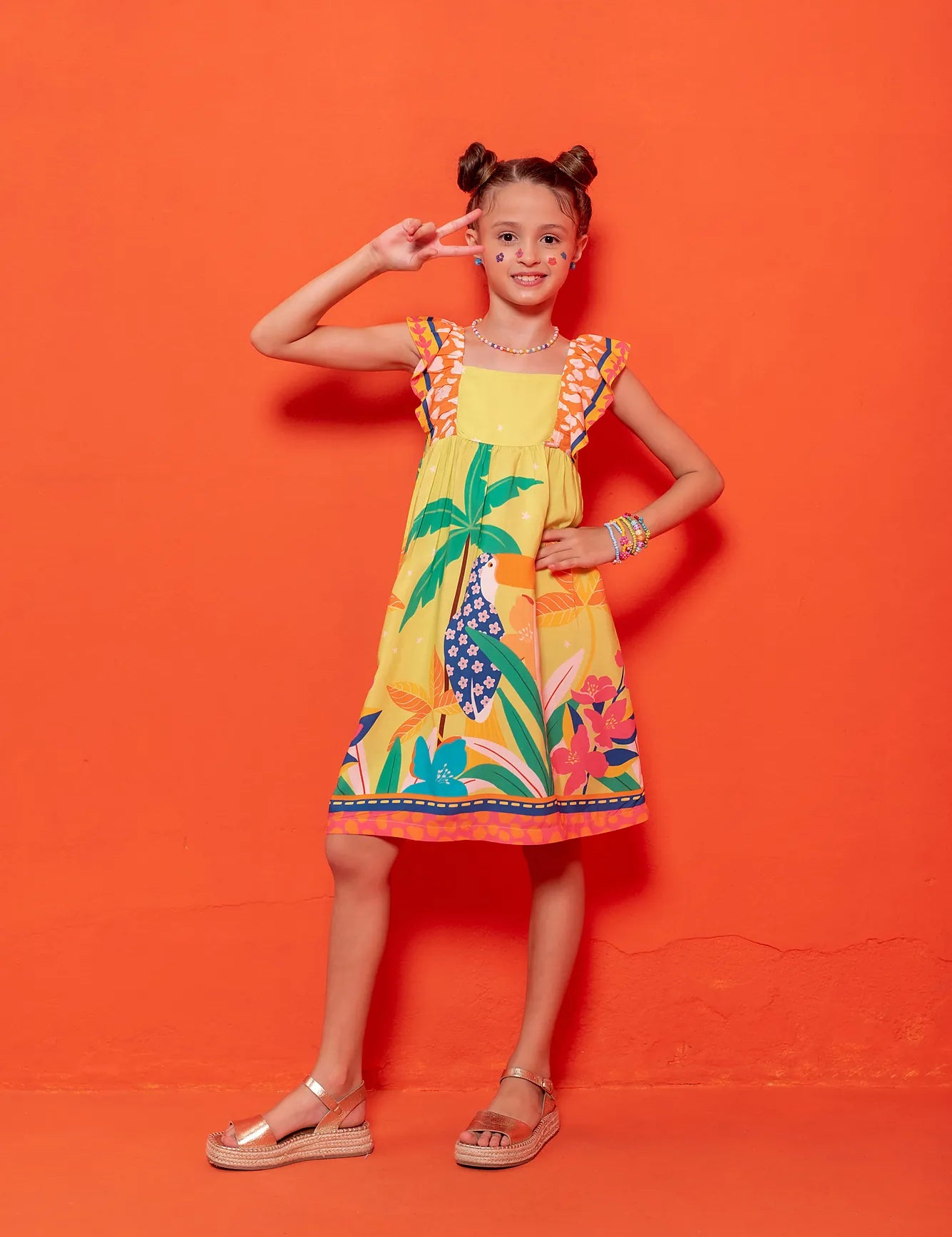 Vestido infantil com estampa tropical de flores e folhas coloridas, alças largas listradas