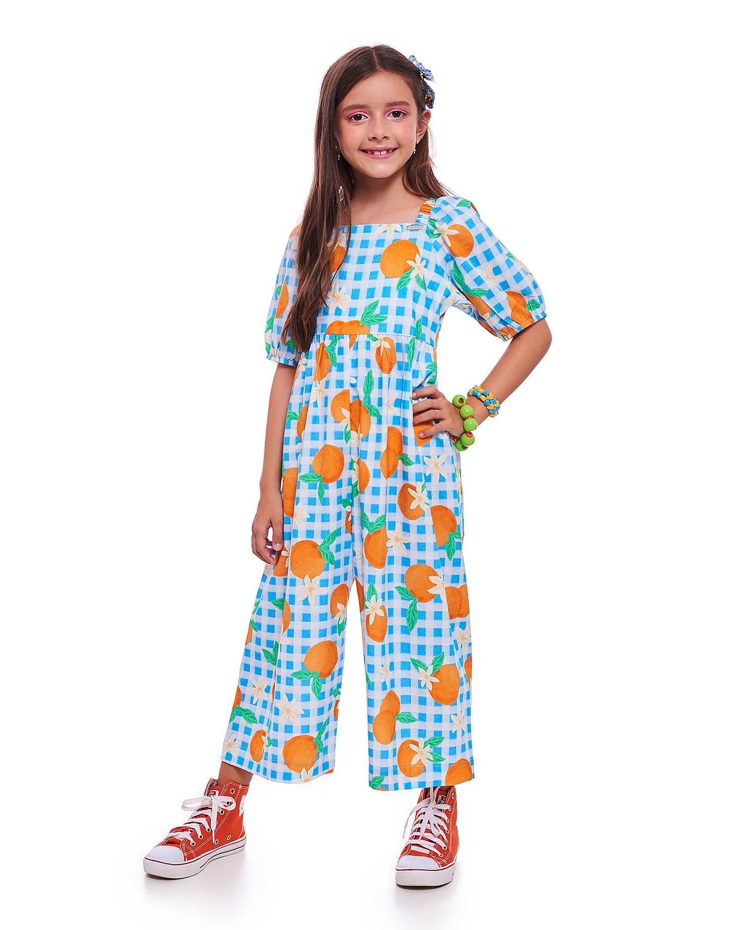 Macacão infantil com estampa de bergamotas em fundo azul xadrez e mangas bufantes