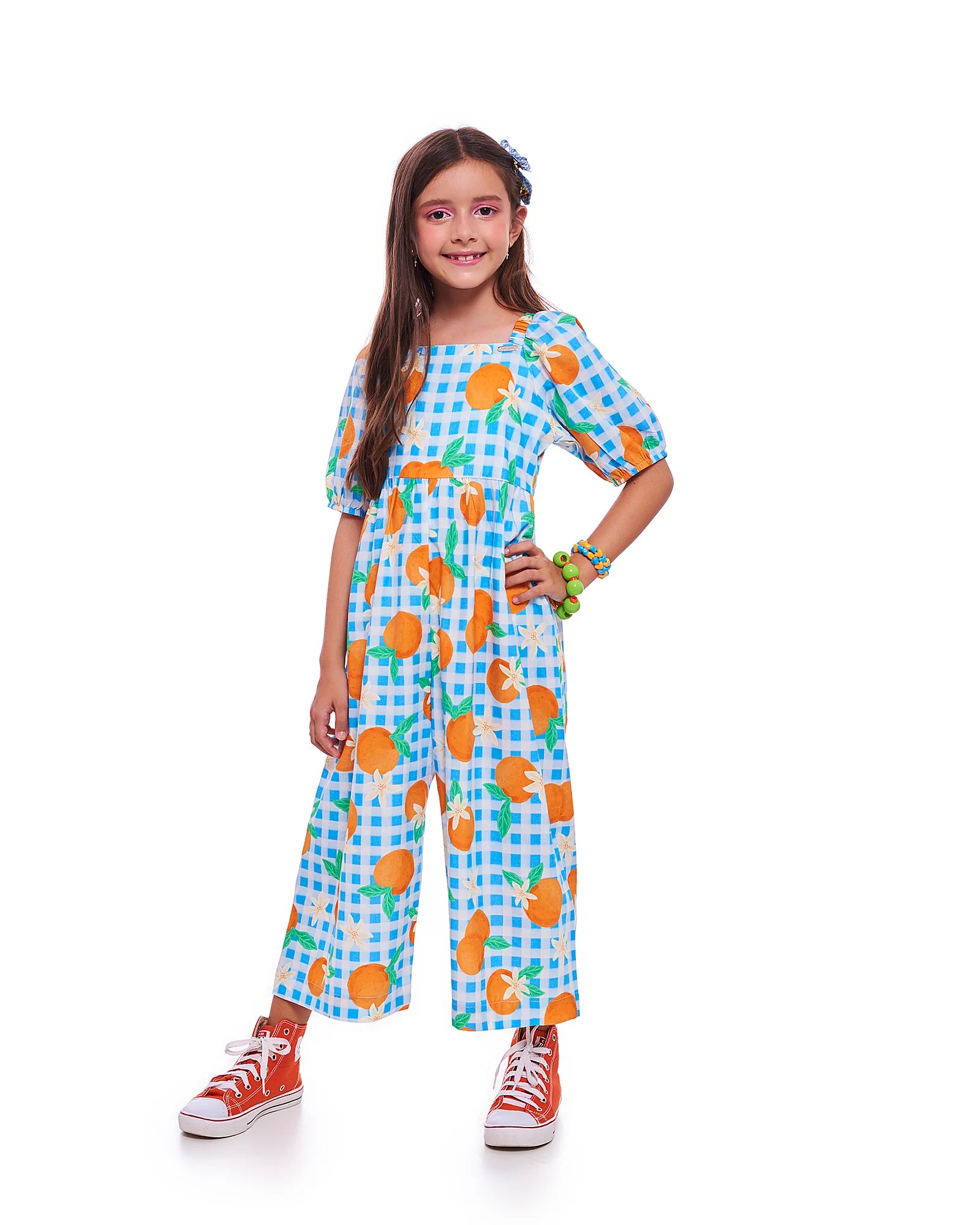 Macacão infantil com estampa de bergamotas em fundo azul xadrez e mangas bufantes