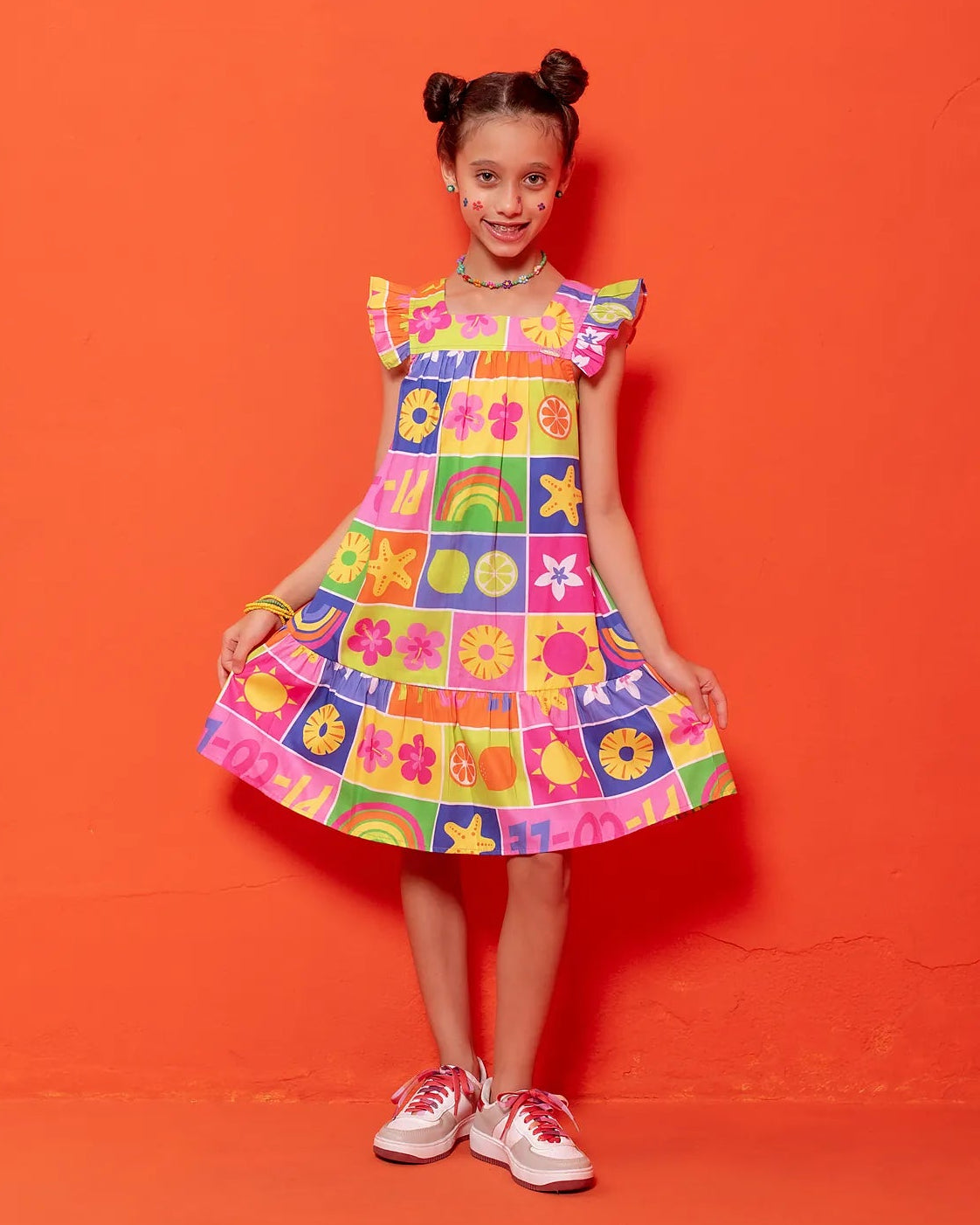 Vestido infantil com estampa colorida de flores e formas geométricas, alças largas e babados na barra