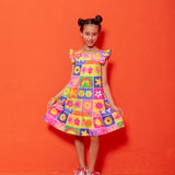 Vestido infantil com estampa colorida de flores e formas geométricas, alças largas e babados na barra