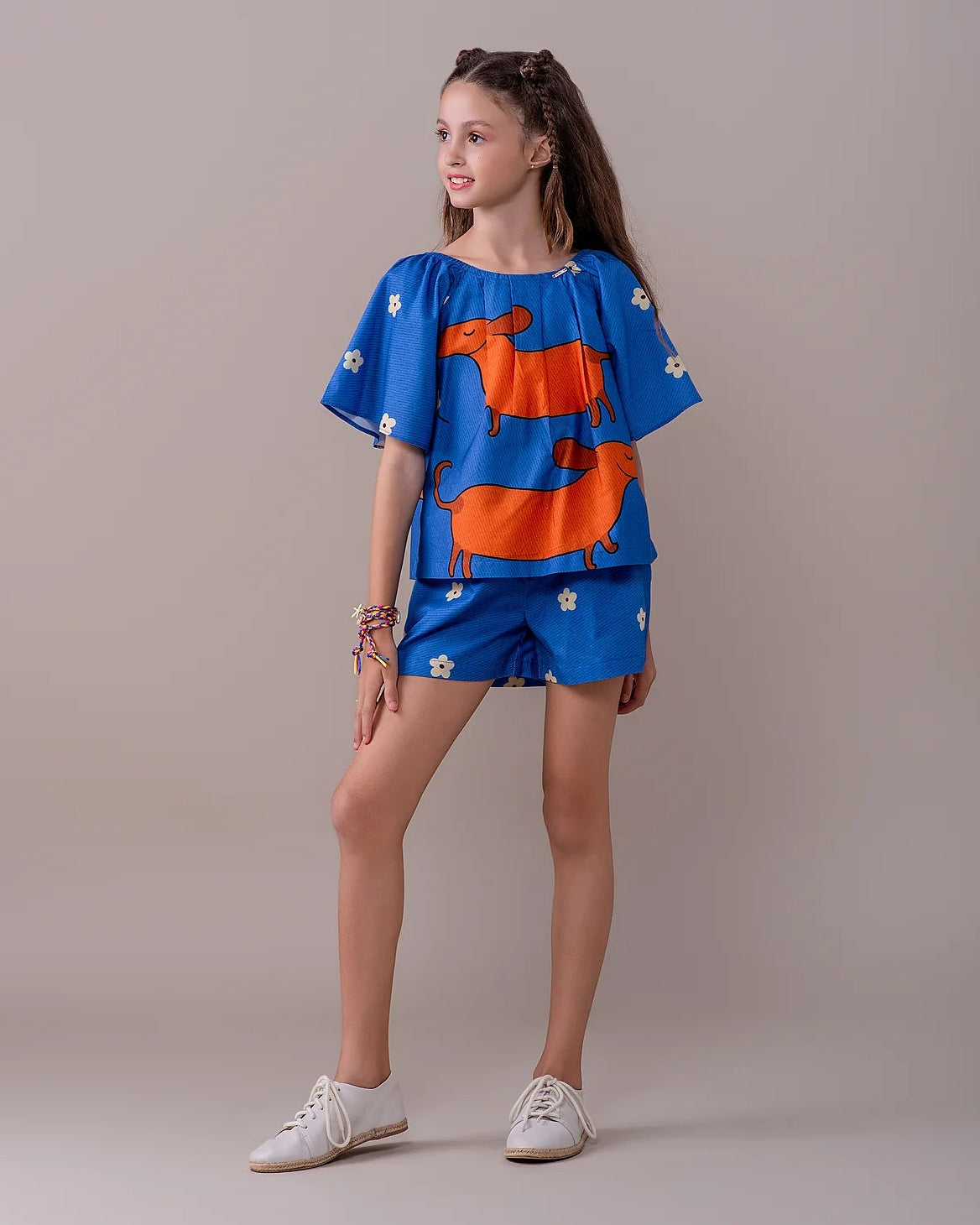 Conjunto infantil feminino com blusa azul de mangas bufantes e saia-short, estampa de cães salsichas e flores