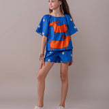 Conjunto infantil feminino com blusa azul de mangas bufantes e saia-short, estampa de cães salsichas e flores