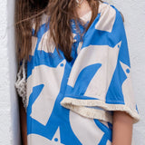 Vestido infantil com estampa geométrica em azul e creme, mangas amplas e gola arredondada