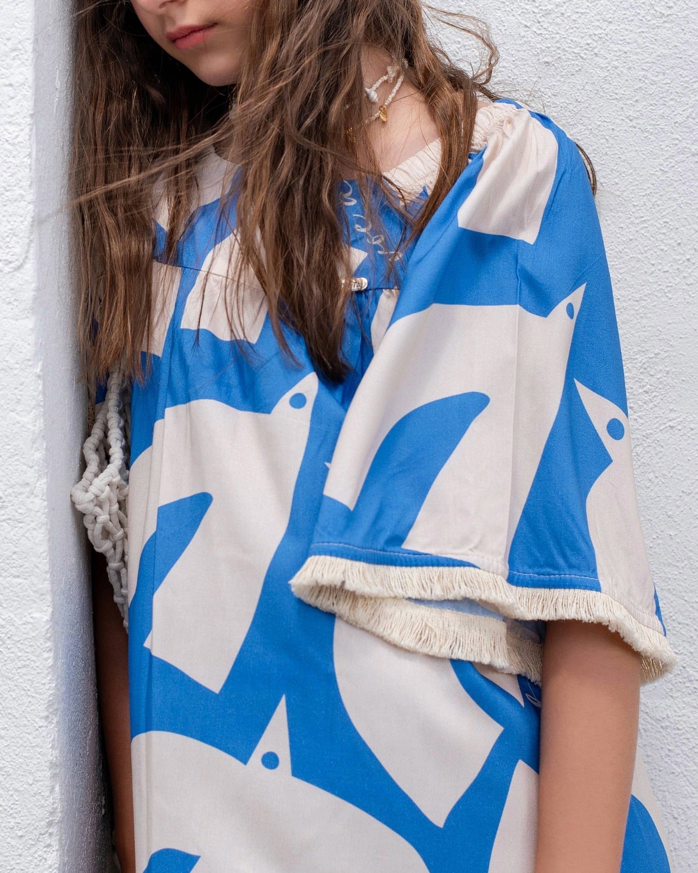 Vestido infantil com estampa geométrica em azul e creme, mangas amplas e gola arredondada