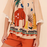 Conjunto infantil com blusa de mangas amplas e shorts laranja, estampa de elefante e natureza