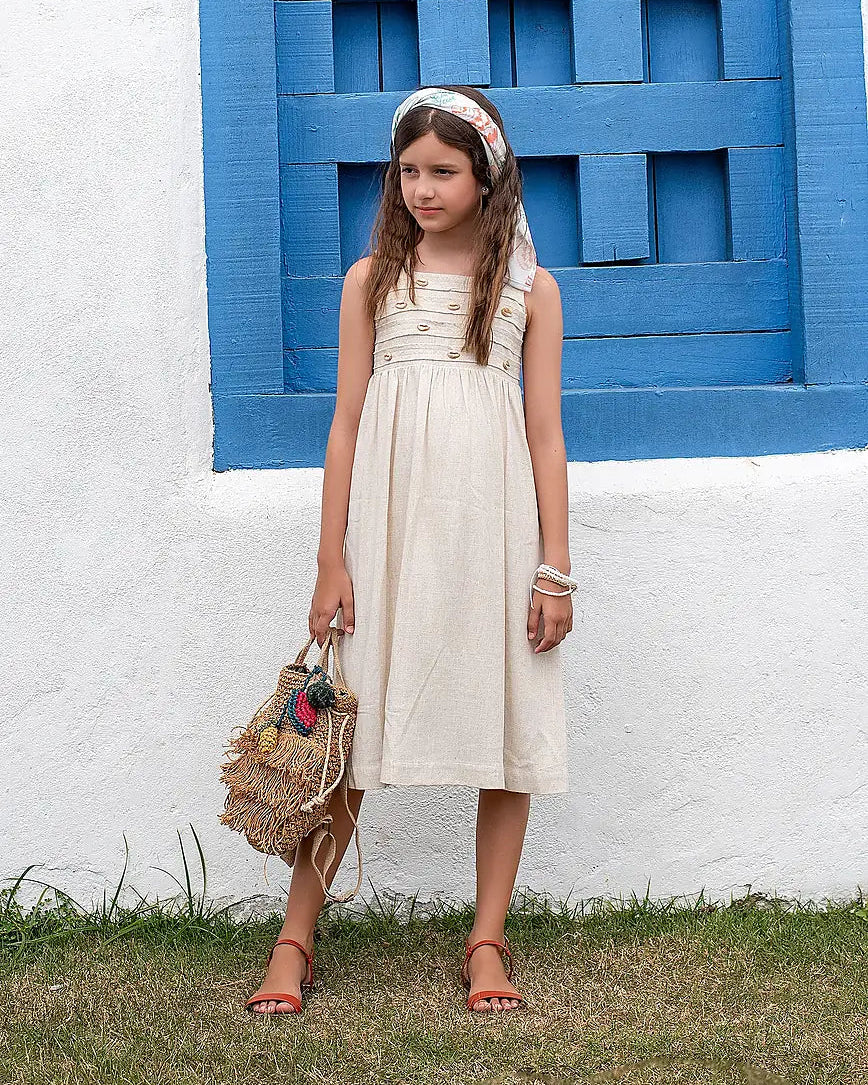 Vestido feminino infantil com alças largas e botões frontais, tom neutro e saia ampla
