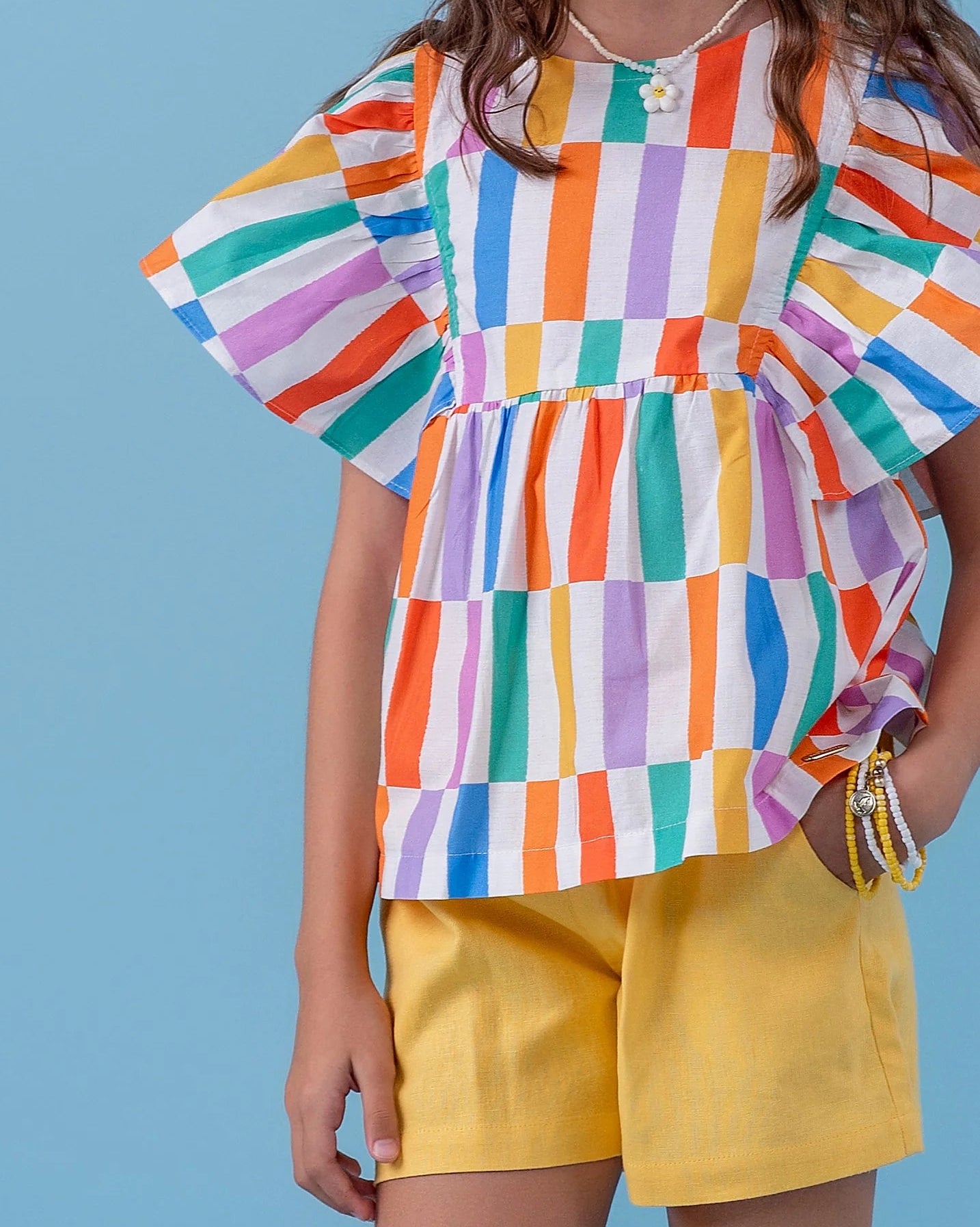 Conjunto infantil feminino com blusa de mangas amplas e short amarelo, estampa de listras coloridas