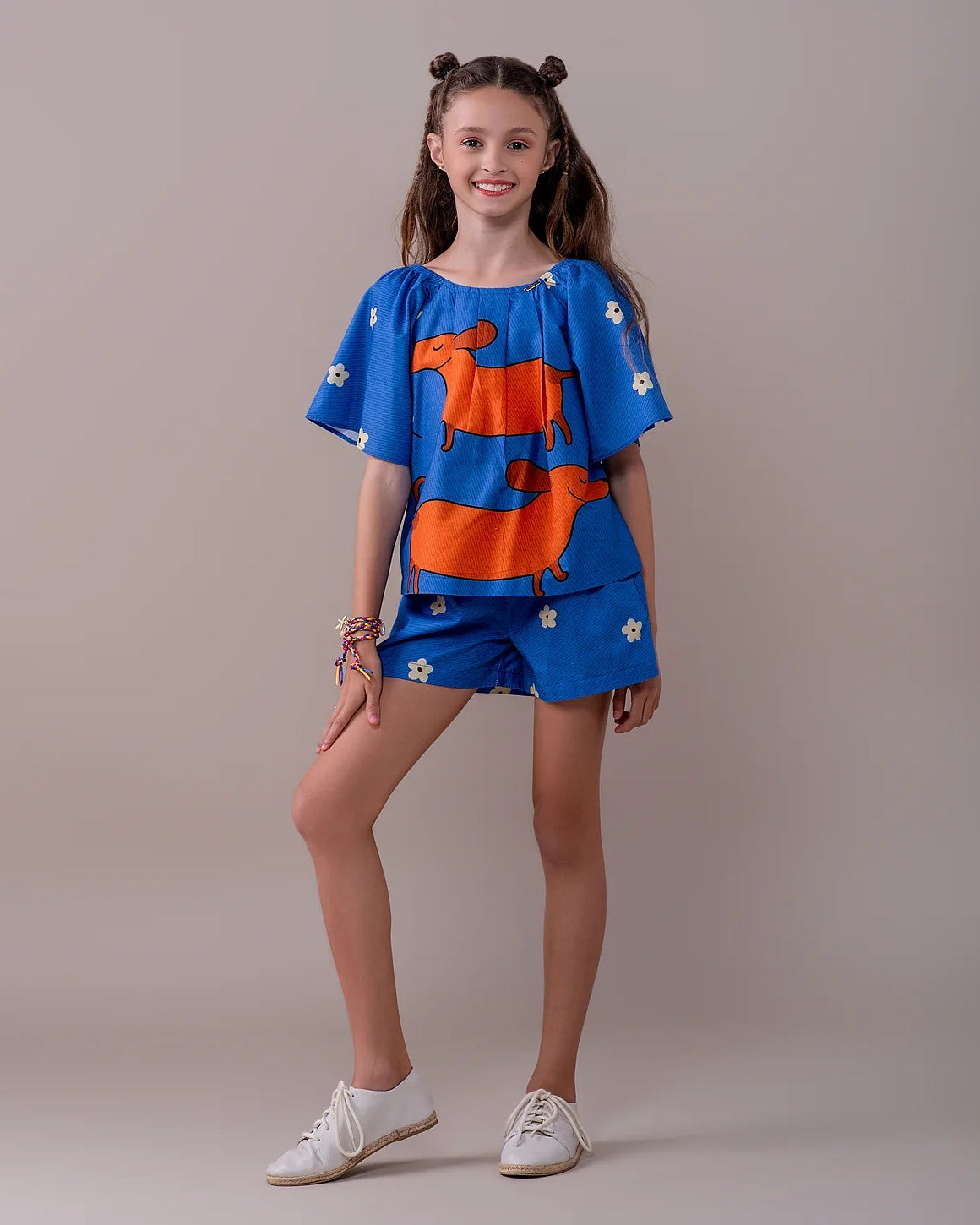 Conjunto infantil feminino com blusa azul de mangas bufantes e saia-short, estampa de cães salsichas e flores