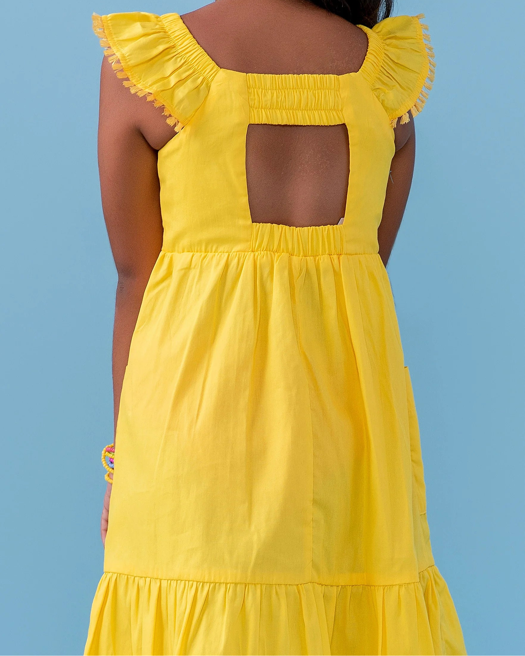 Vestido amarelo infantil com alças largas e saia rodada, detalhe de botões nas alças