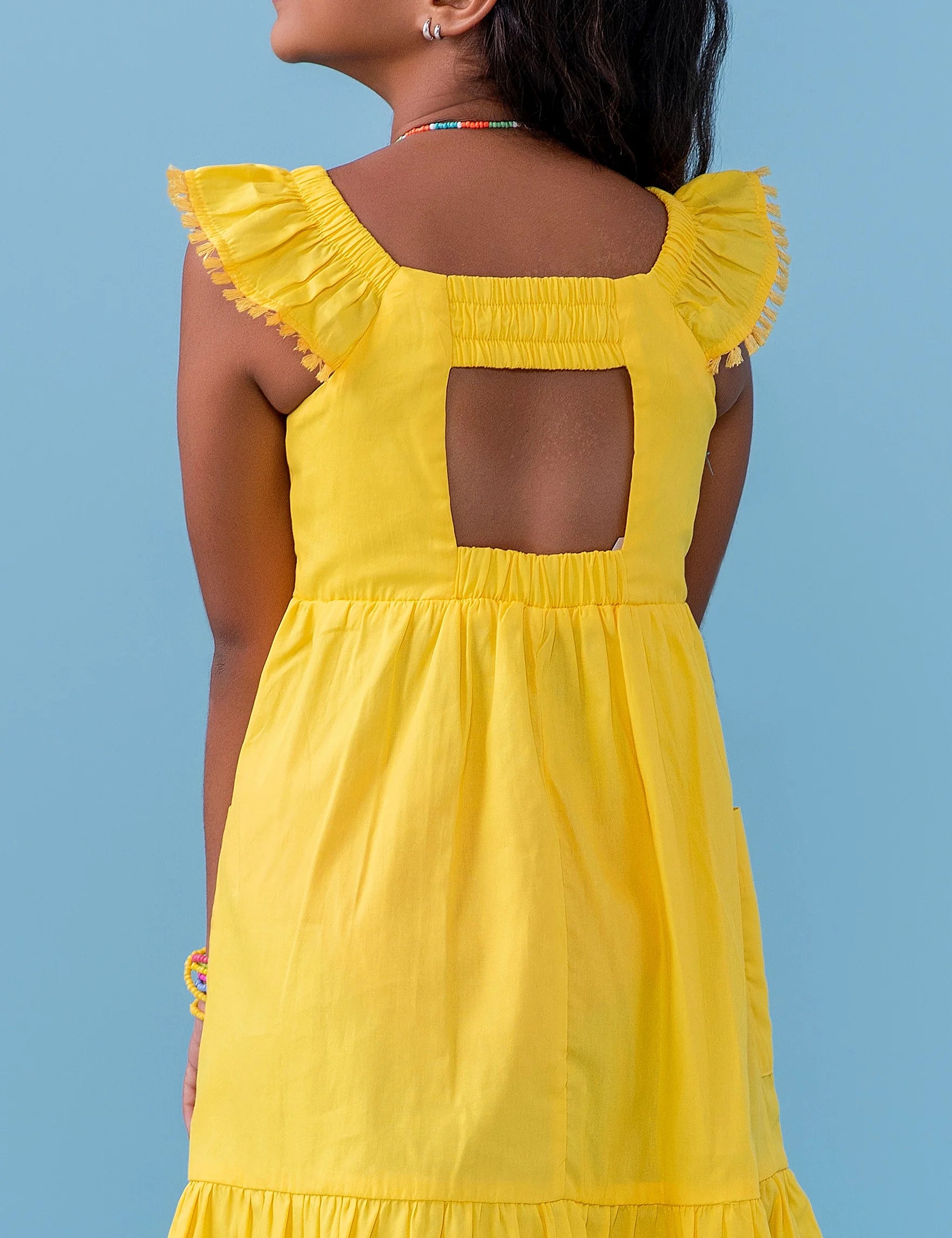 Vestido amarelo infantil com alças largas e saia rodada, detalhe de botões nas alças