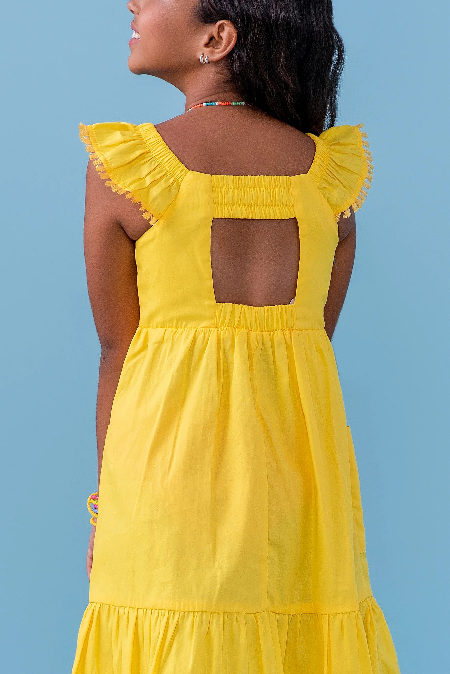 Vestido amarelo infantil com alças largas e saia rodada, detalhe de botões nas alças