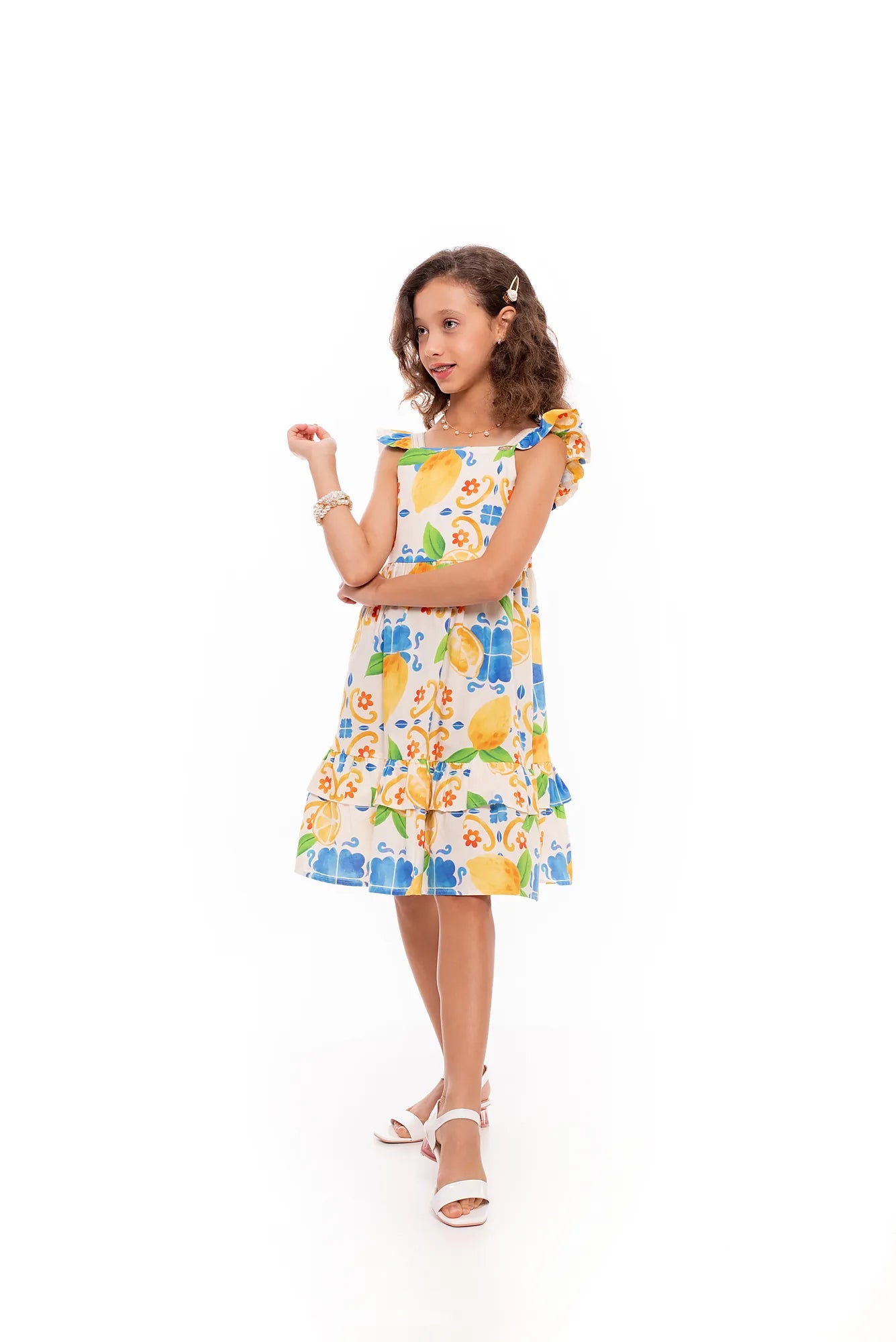 Vestido infantil com estampa de limões e flores em tons de amarelo e azul, detalhes em babados