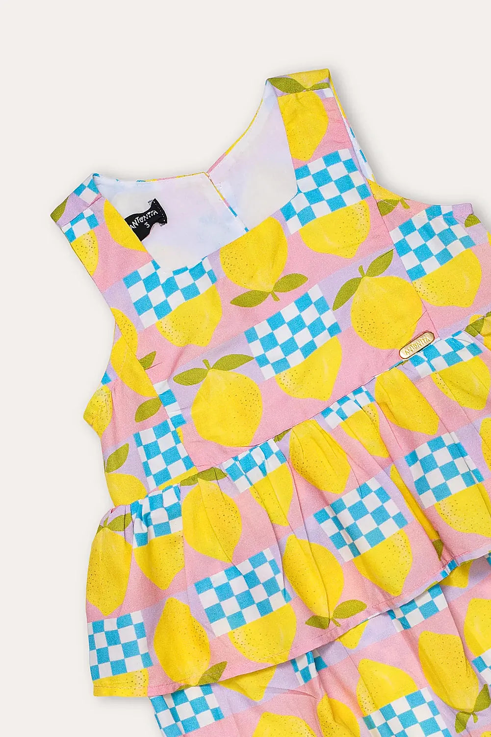 Macacão feminino infantil com estampa de limões e quadrados coloridos, alças largas e saia em camadas.