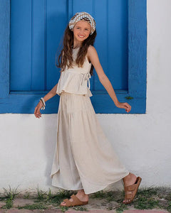 Conjunto feminino infantil com blusa de alças largas e calças amplas em tom claro, detalhe de amarração