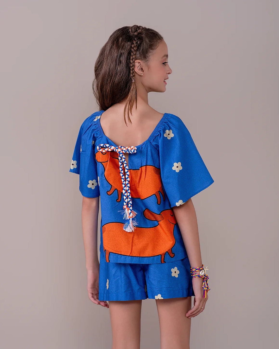 Conjunto infantil feminino com blusa azul de mangas bufantes e saia-short, estampa de cães salsichas e flores