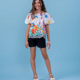 Conjunto feminino infantil com blusa de mangas amplas e short preto, estampa colorida de flores e bolinhas