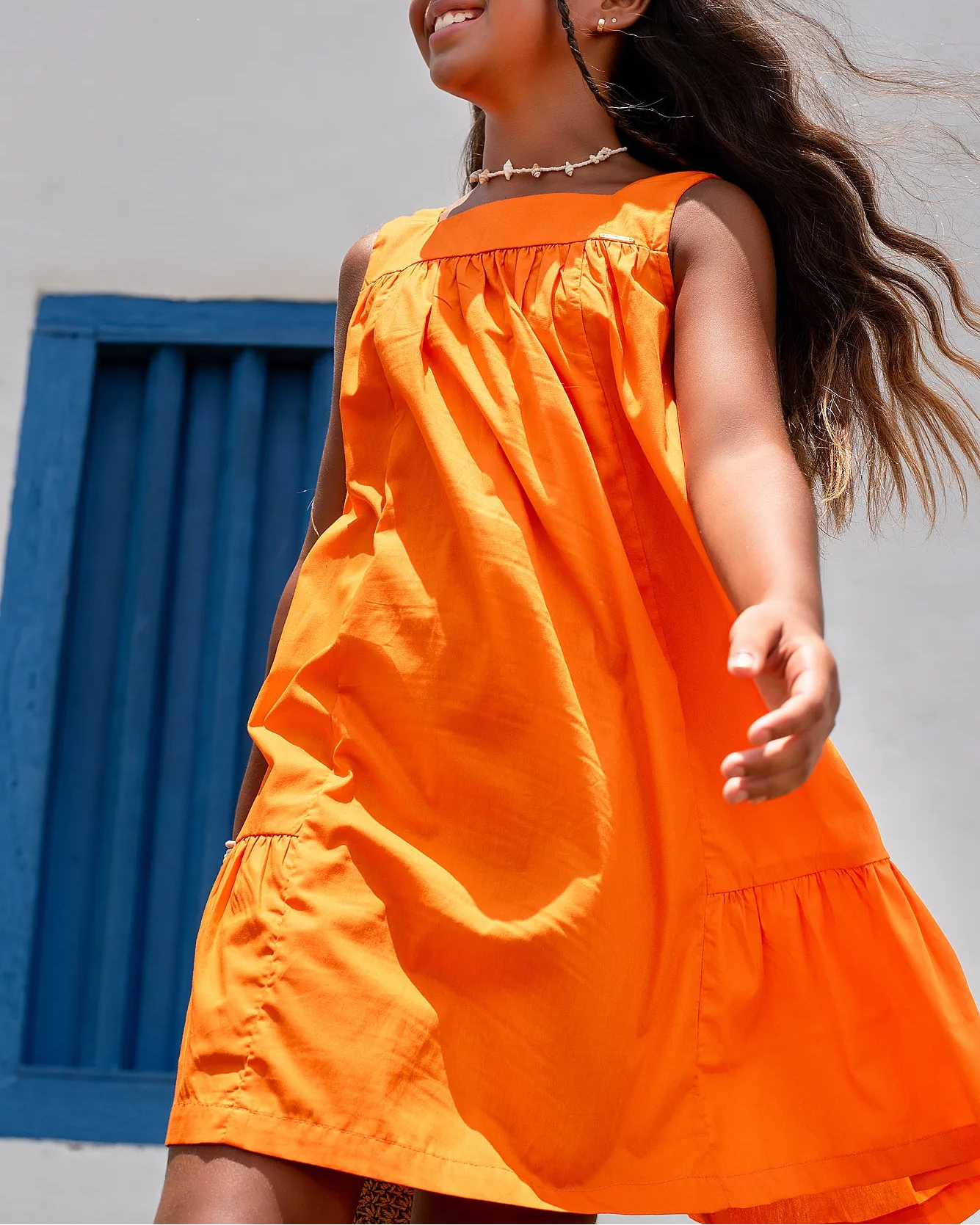 Vestido laranja infantil com alças largas e saia rodada, acabamento em babados