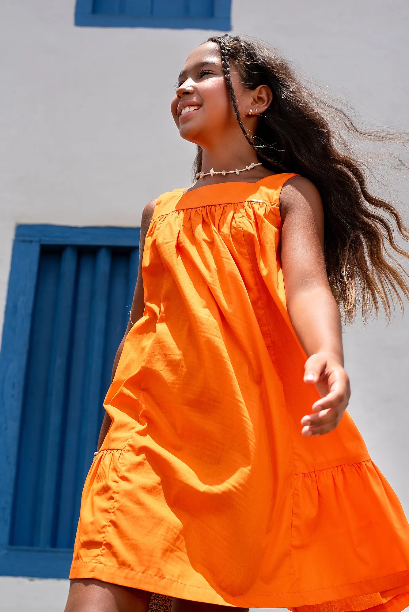 Vestido laranja infantil com alças largas e saia rodada, acabamento em babados