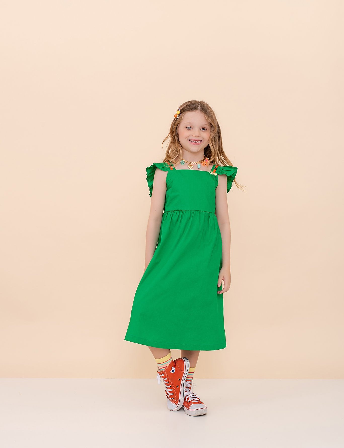 Vestido verde infantil com alças largas e detalhes coloridos, saia ampla